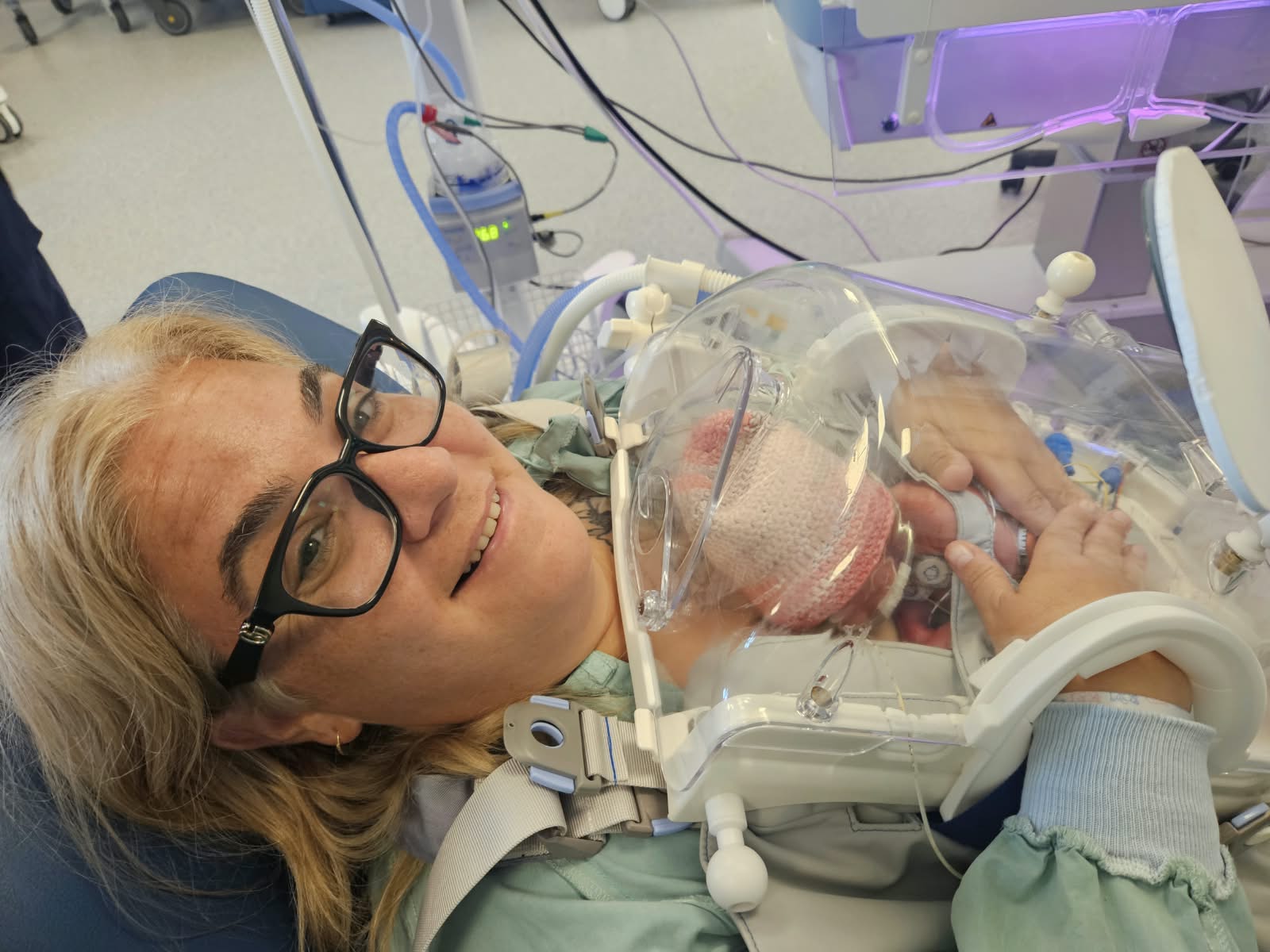 A smiling mother holding her preterm baby on her chest in the Skincubator